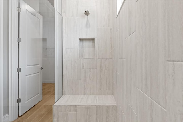 bathroom with tiled shower and wood-type flooring