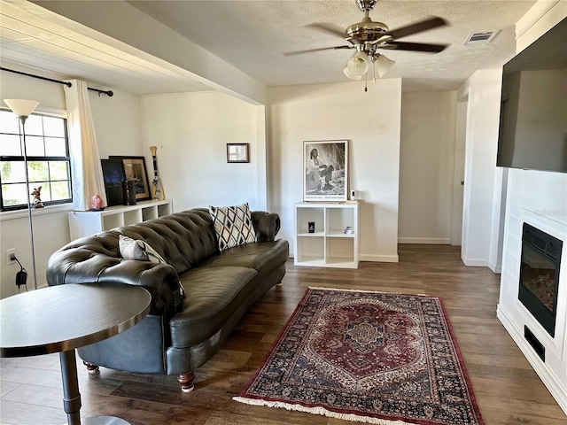 living room with a textured ceiling, wood-type flooring, and ceiling fan