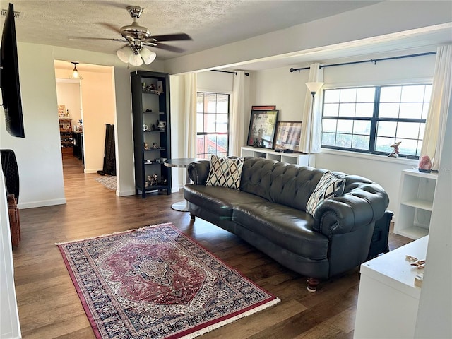 living room featuring ceiling fan, a textured ceiling, and dark hardwood / wood-style flooring