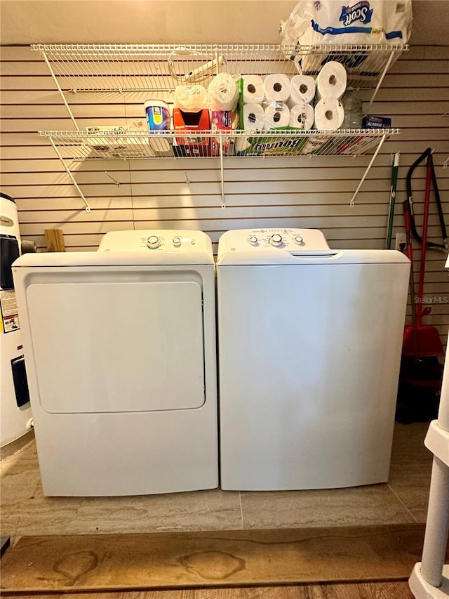 laundry area with washing machine and dryer and wooden walls