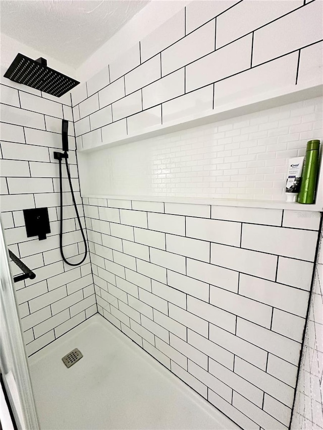 bathroom featuring a textured ceiling and a tile shower