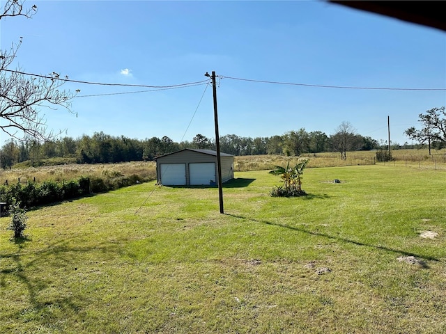 view of yard featuring an outbuilding, a garage, and a rural view