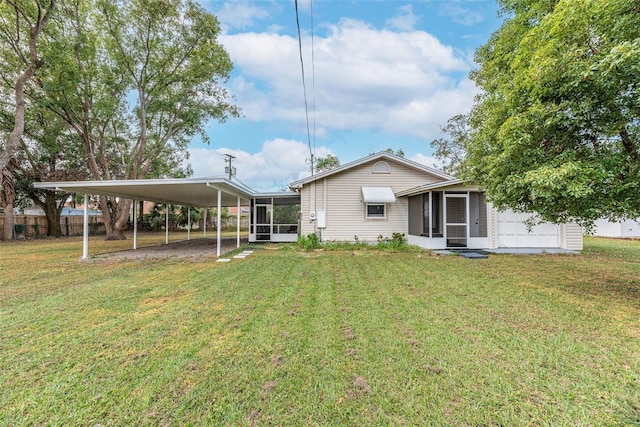 rear view of property with a sunroom, a lawn, and a carport