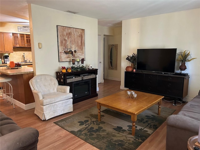 living room featuring sink and light hardwood / wood-style flooring