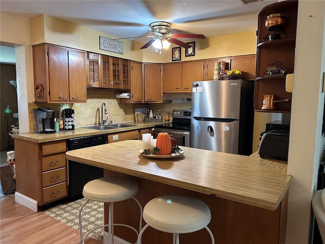 kitchen featuring backsplash, appliances with stainless steel finishes, a kitchen bar, sink, and kitchen peninsula