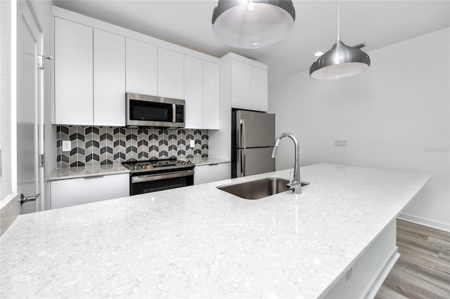 kitchen with white cabinets, decorative light fixtures, sink, and stainless steel appliances