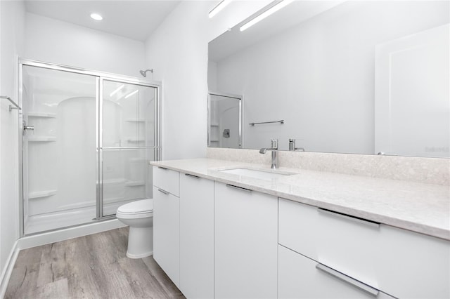 bathroom with vanity, wood-type flooring, an enclosed shower, and toilet