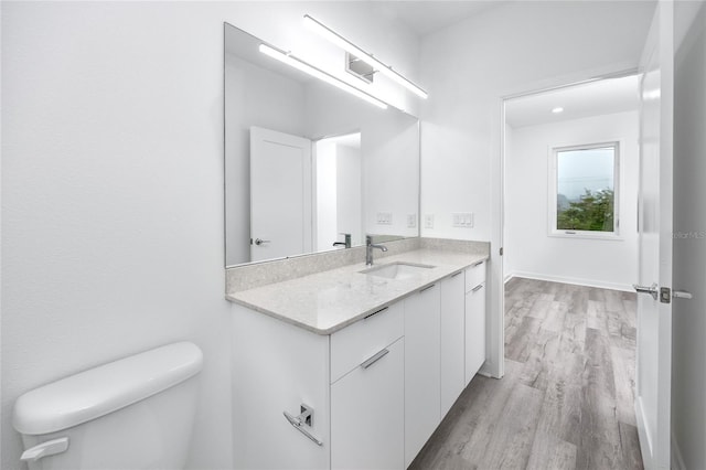 bathroom with wood-type flooring, vanity, and toilet