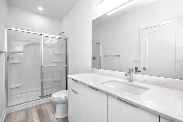 bathroom featuring hardwood / wood-style floors, vanity, an enclosed shower, and toilet