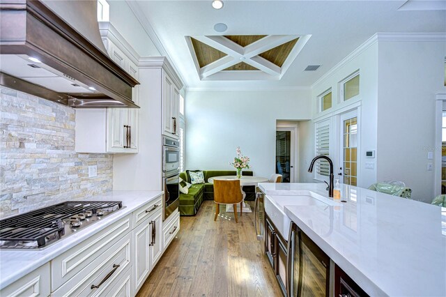 kitchen featuring white cabinets, light hardwood / wood-style floors, custom range hood, and appliances with stainless steel finishes