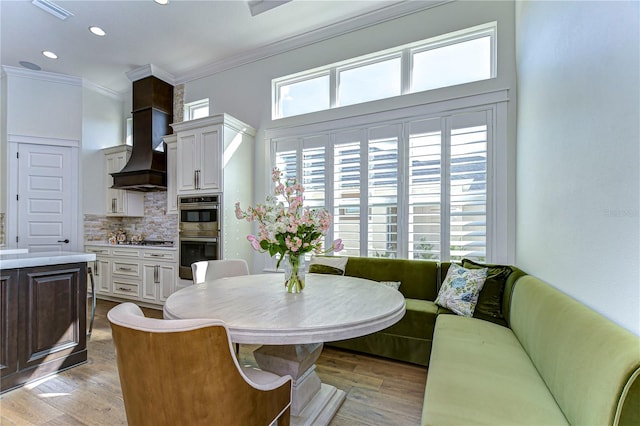 dining room with breakfast area, light hardwood / wood-style floors, and ornamental molding