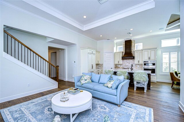 living room featuring a tray ceiling, crown molding, and dark wood-type flooring