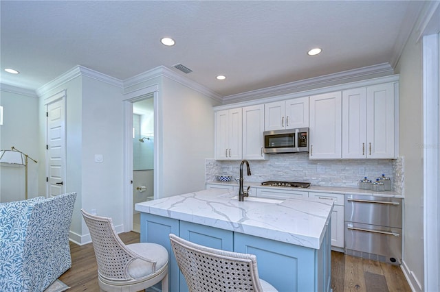 kitchen with white cabinetry, a center island with sink, stainless steel appliances, and wood-type flooring