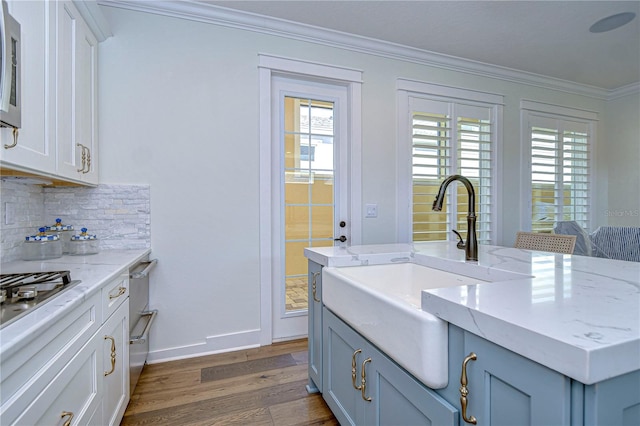 kitchen with sink, light stone counters, dark hardwood / wood-style floors, decorative backsplash, and ornamental molding