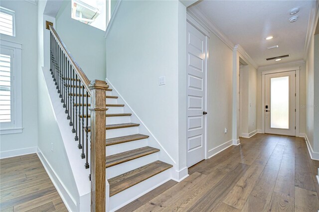 entryway with plenty of natural light, wood-type flooring, and crown molding