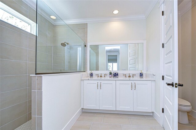 bathroom featuring tile patterned floors, crown molding, toilet, tiled shower, and vanity