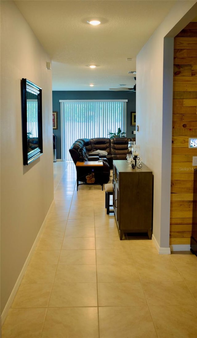 hall with wooden walls and light tile patterned floors