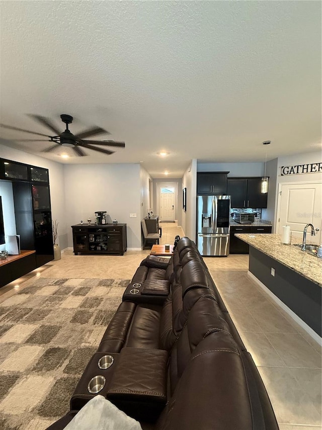 tiled living room with ceiling fan, a textured ceiling, and sink