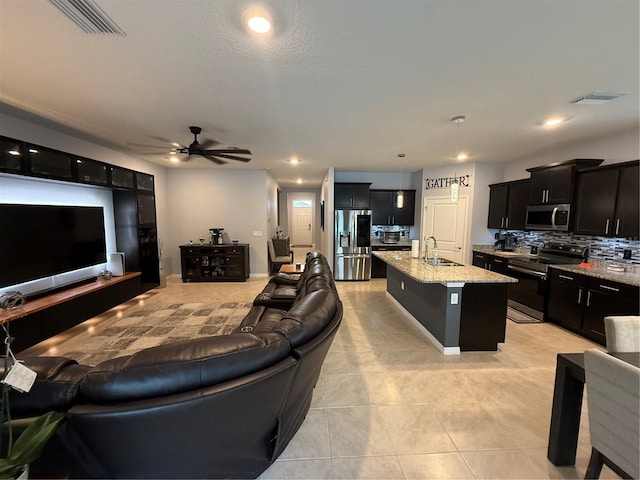 tiled living room with a textured ceiling, ceiling fan, and sink