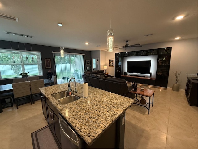 kitchen with light stone counters, sink, an island with sink, stainless steel dishwasher, and ceiling fan