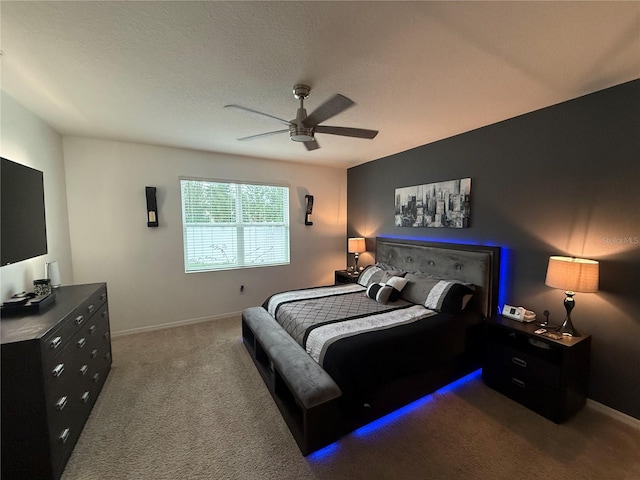 carpeted bedroom featuring ceiling fan and a textured ceiling