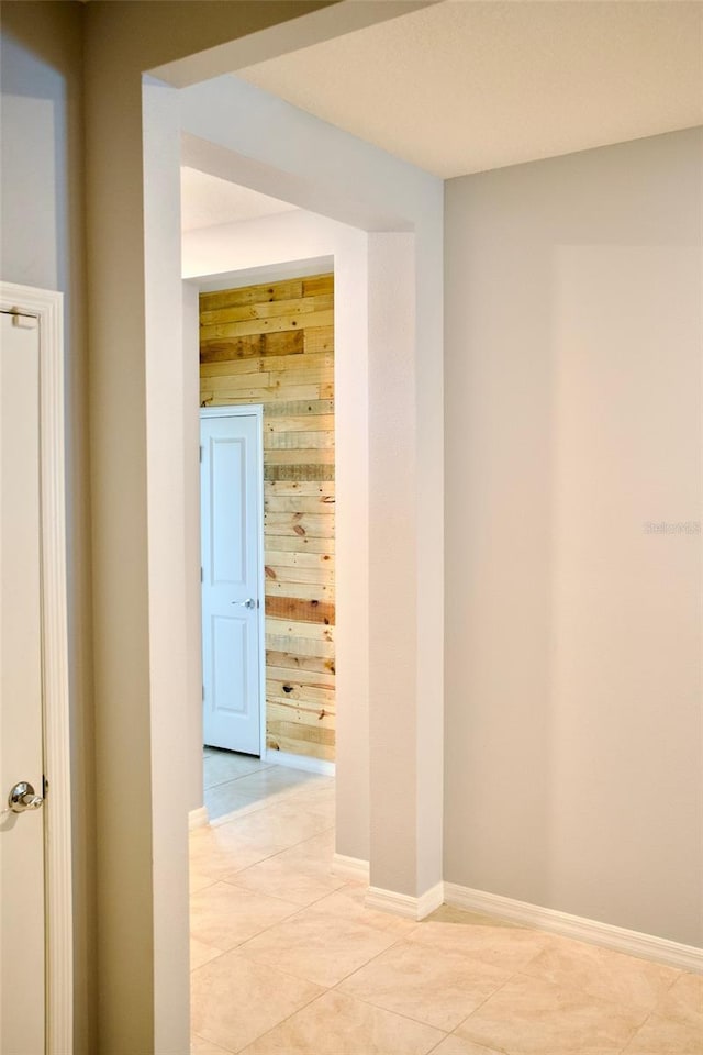 corridor with wooden walls and light tile patterned flooring