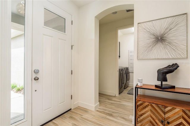 foyer entrance featuring washer and clothes dryer and light wood-type flooring