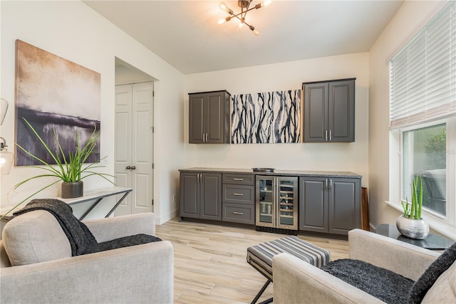 bar featuring beverage cooler, light hardwood / wood-style floors, and gray cabinetry