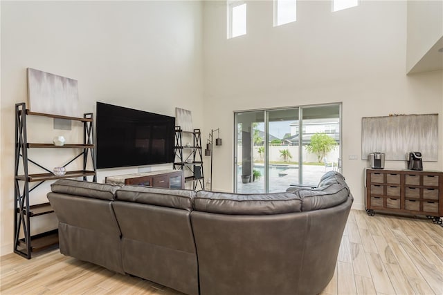 living room featuring light hardwood / wood-style floors, a high ceiling, and a wealth of natural light