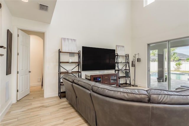 living room with a towering ceiling and light hardwood / wood-style flooring