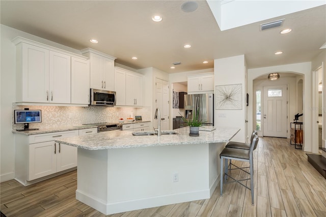 kitchen featuring sink, an island with sink, white cabinets, and appliances with stainless steel finishes