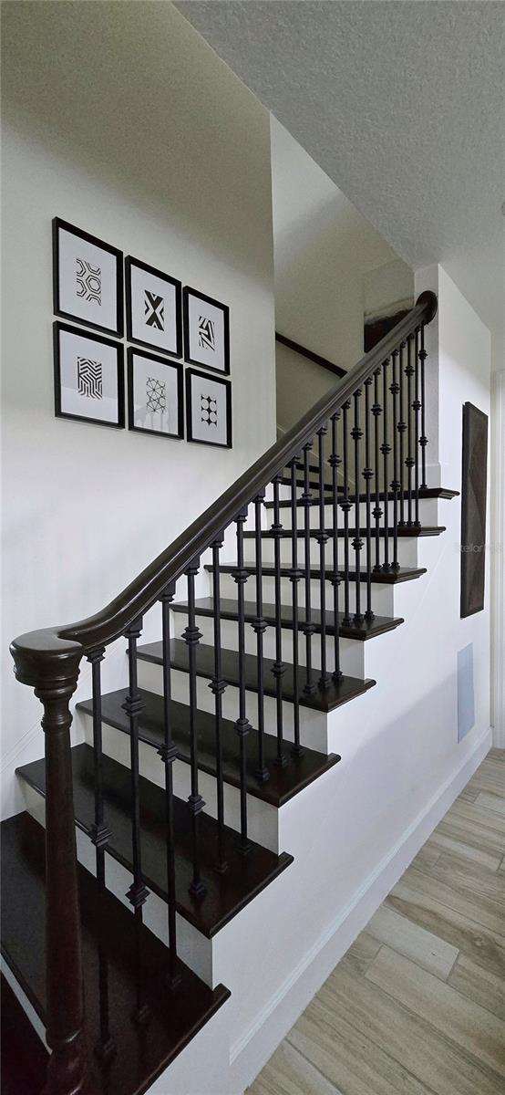 stairs with hardwood / wood-style flooring and a textured ceiling