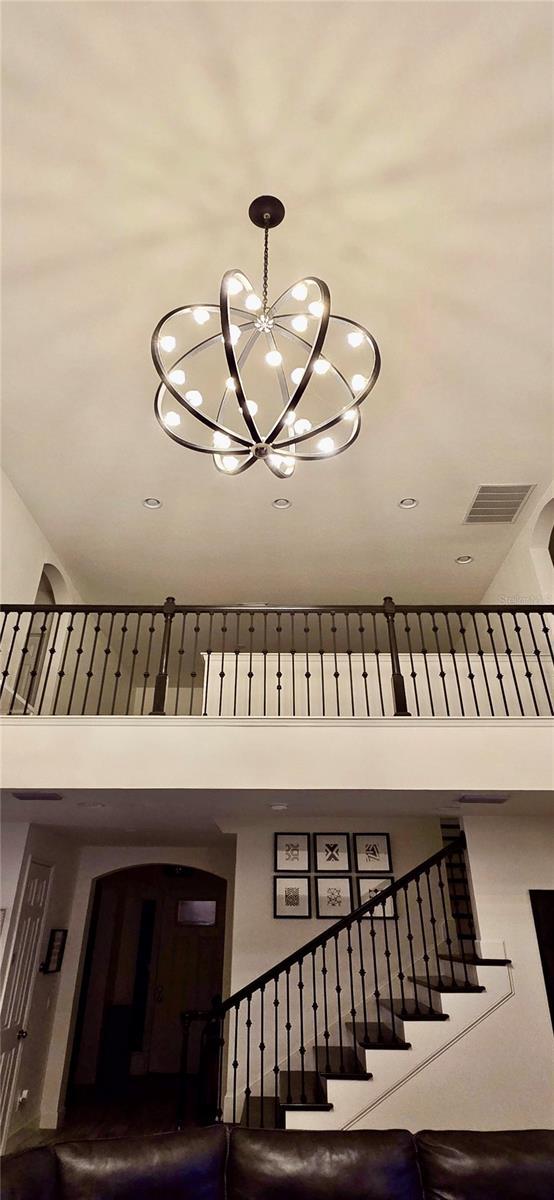 stairway featuring a towering ceiling and a notable chandelier