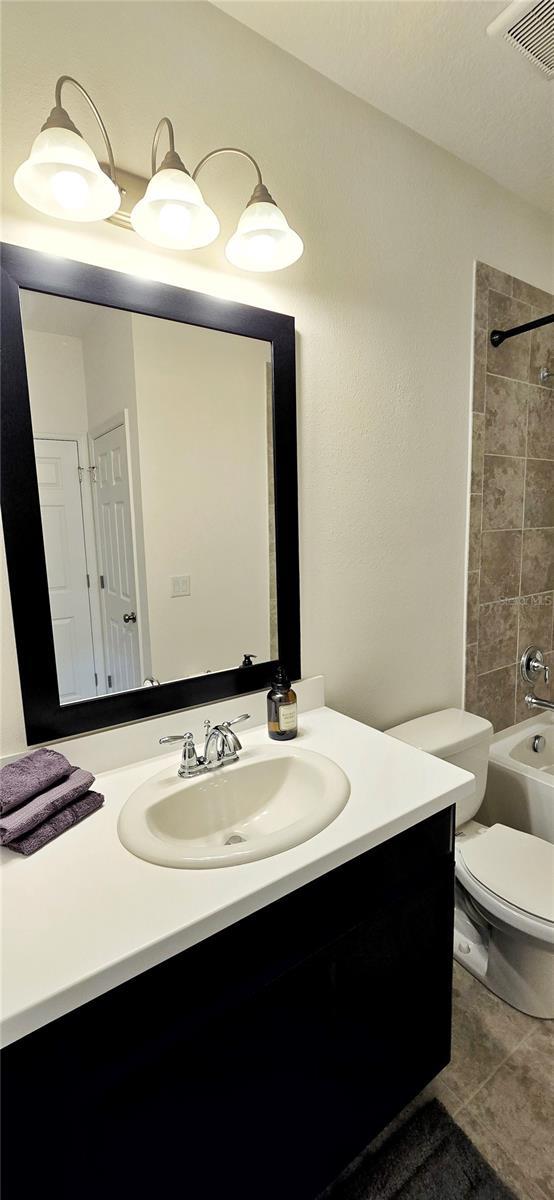 full bathroom featuring vanity, toilet, tiled shower / bath combo, and tile patterned flooring