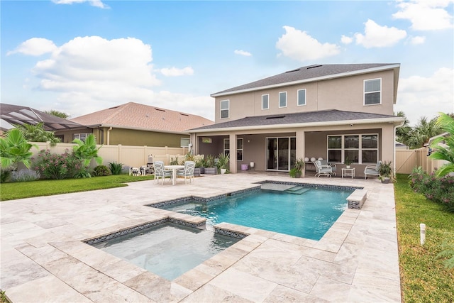 rear view of property featuring a swimming pool with hot tub, a yard, and a patio