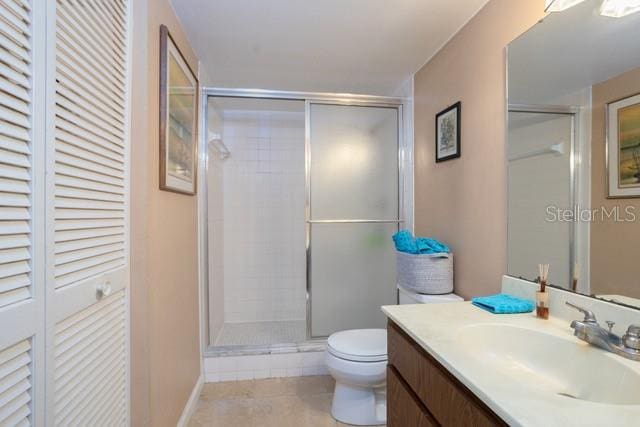 bathroom featuring toilet, vanity, tile patterned flooring, and walk in shower