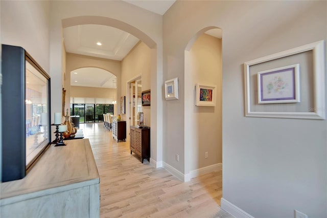 hallway featuring light hardwood / wood-style floors and a tray ceiling