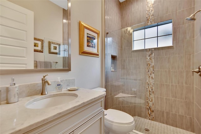 bathroom with toilet, vanity, and tiled shower