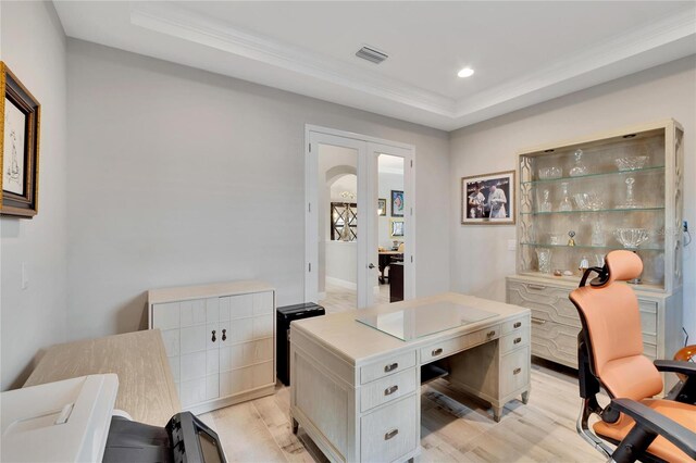 office area with light hardwood / wood-style floors and a tray ceiling