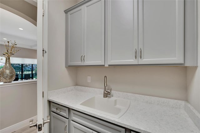 kitchen with gray cabinets, sink, and light stone counters