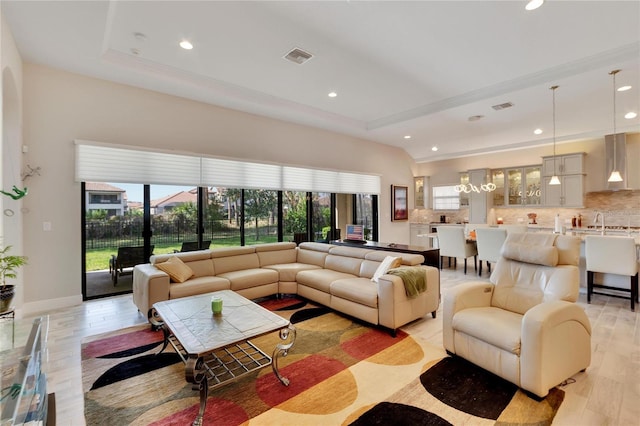 living room with light wood-type flooring and a tray ceiling