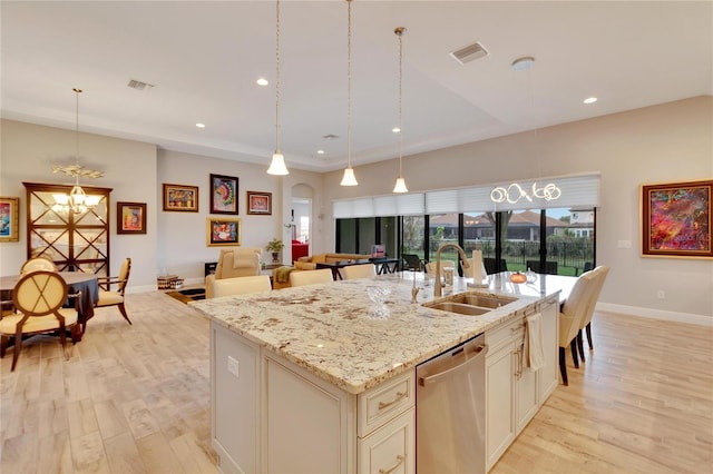 kitchen featuring light hardwood / wood-style floors, hanging light fixtures, sink, and an island with sink