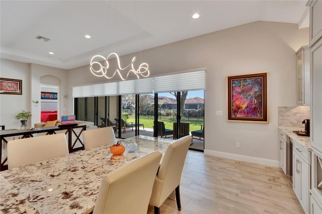 dining space featuring a raised ceiling and light wood-type flooring