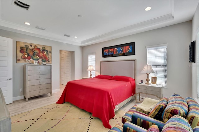 bedroom featuring multiple windows, light hardwood / wood-style floors, and a raised ceiling