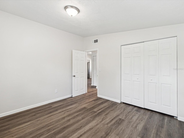 unfurnished bedroom featuring dark hardwood / wood-style flooring and a closet