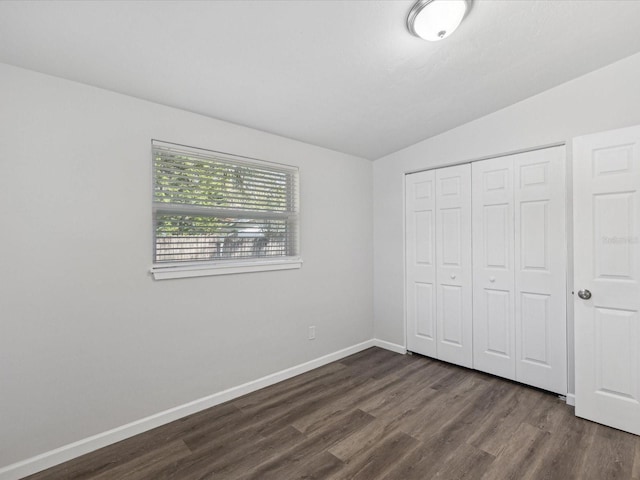 unfurnished bedroom featuring vaulted ceiling, a closet, and dark hardwood / wood-style flooring