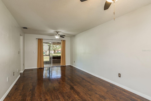 unfurnished room with dark wood-style floors, a ceiling fan, visible vents, and baseboards