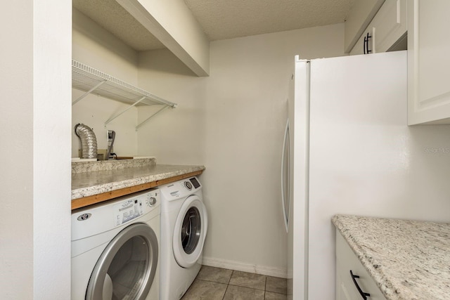 clothes washing area with washing machine and clothes dryer, light tile patterned flooring, a textured ceiling, laundry area, and baseboards