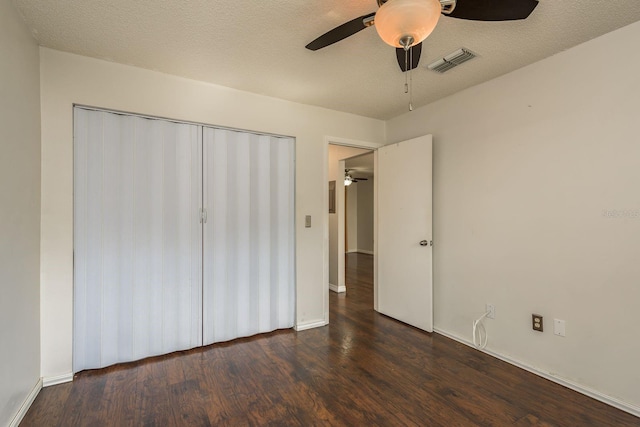 unfurnished bedroom featuring a closet, a textured ceiling, visible vents, and wood finished floors