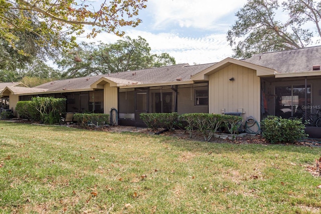 rear view of property featuring a yard and a sunroom